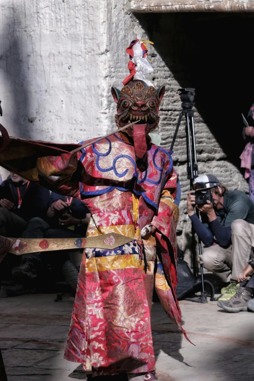 a woman in oriental clothing walking next to a wall