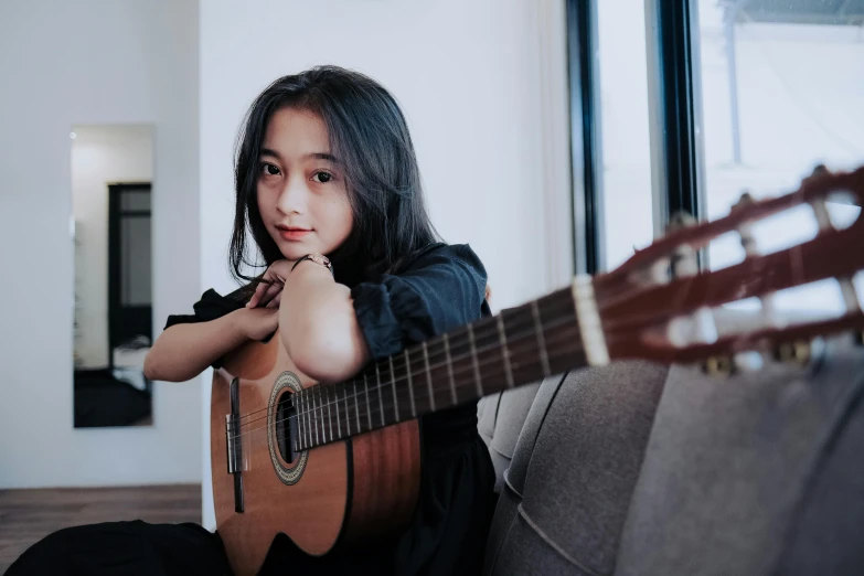 a woman sitting on a couch holding a guitar