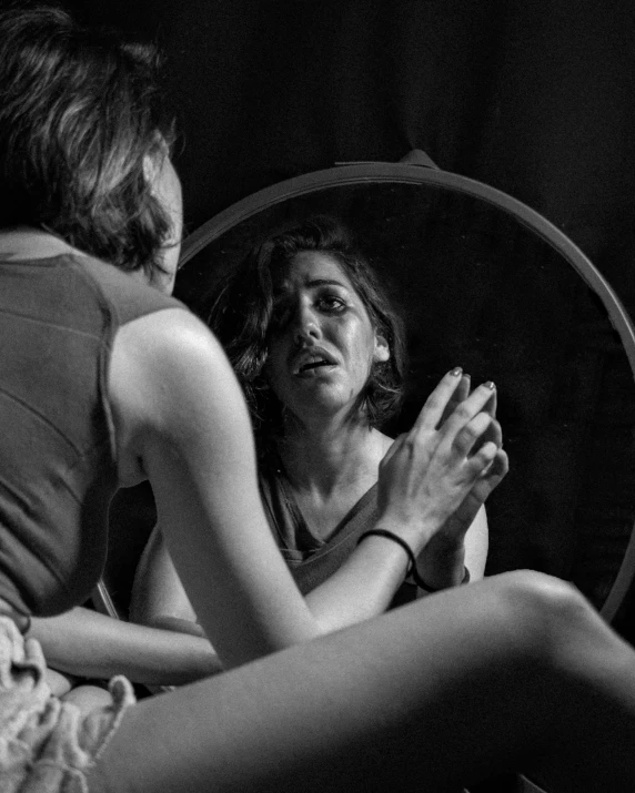 a woman sitting in front of a mirror brushing her teeth