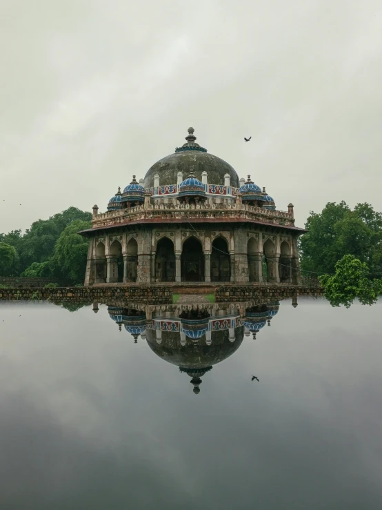 a dome shaped building stands on the edge of a body of water with several statues on top