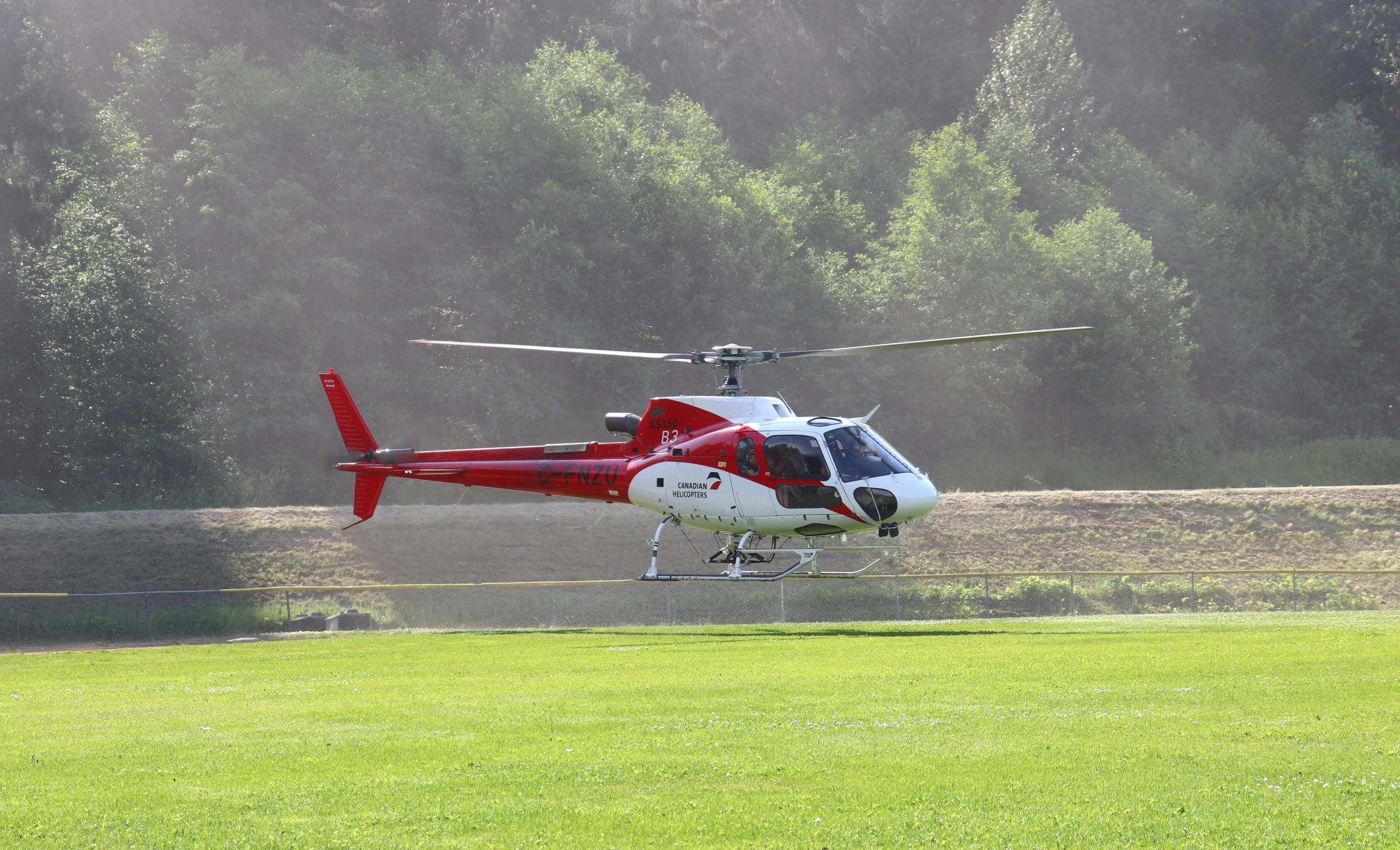 a red and white helicopter sitting on top of grass