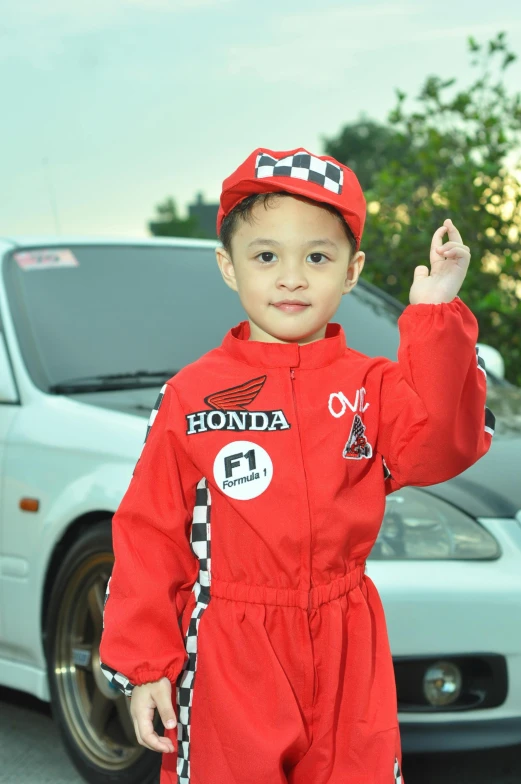 a boy is standing in front of a car waving
