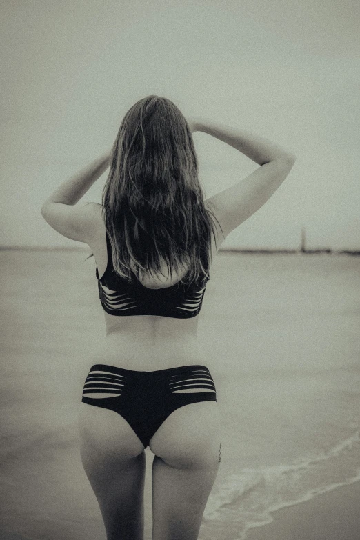 a woman standing in front of the ocean in her swim suit