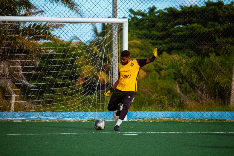 a boy wearing a yellow shirt kicking a soccer ball