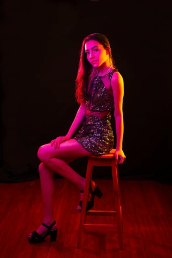 a beautiful young woman wearing a short skirt sitting on a stool