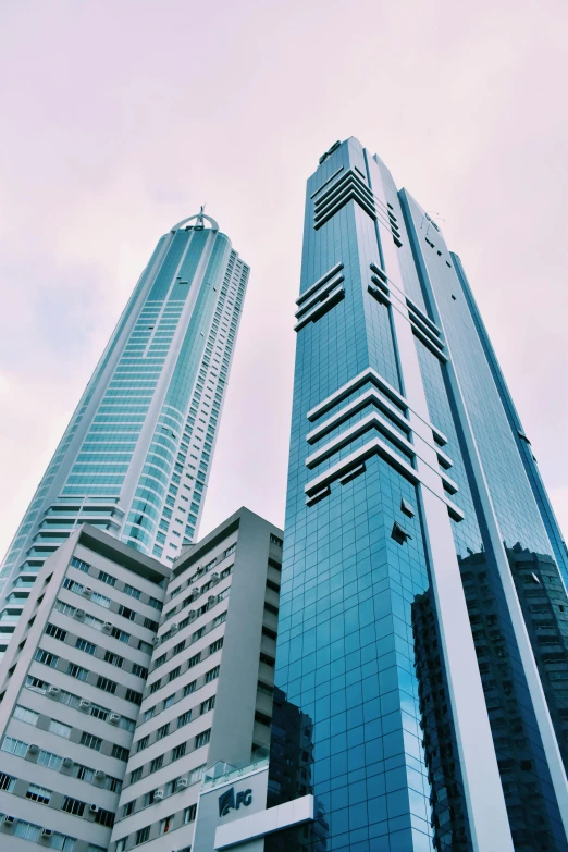 two skyscrs are seen with the clouds in the background