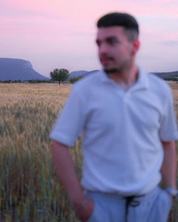 a blurry man standing in front of a wheat field