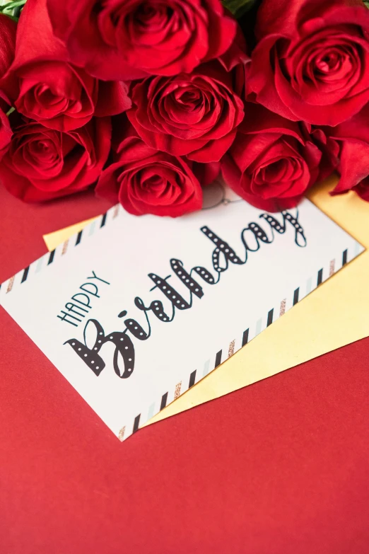 flowers and card saying birthday on red background