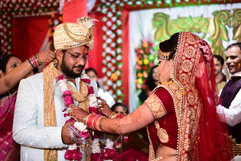 man in traditional indian garb putting garland on woman