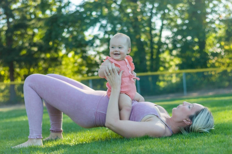 a woman holding a baby in the grass