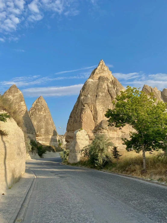 an empty roadway between a row of large hills