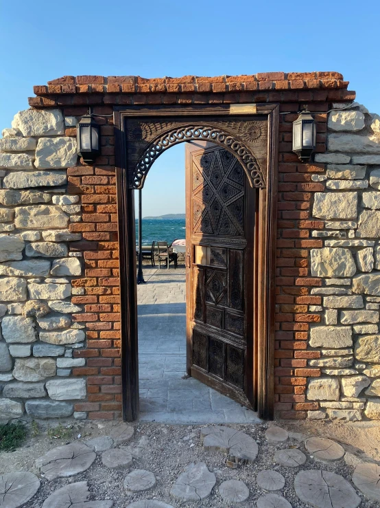 an iron door opens onto a stone walkway overlooking the ocean