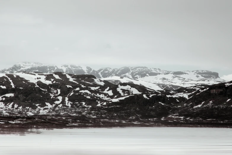 a snowy mountainside with water and trees