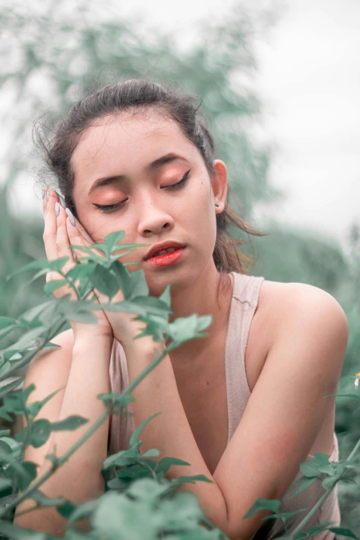 a young woman sitting in grass with her eyes closed