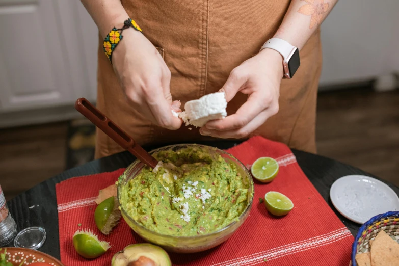 a person making an guacamole dip at a table