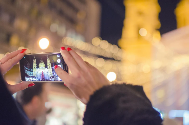 two people holding up cellphones in their hands