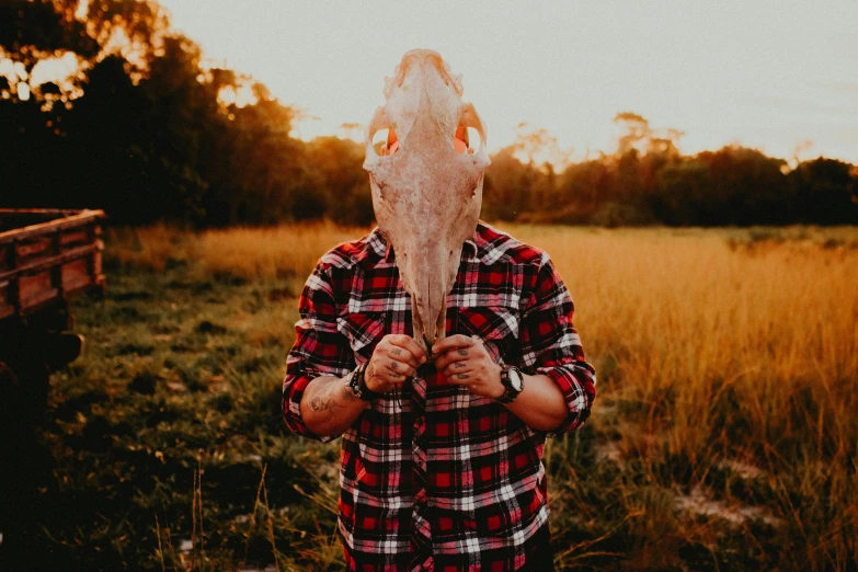 the person is in front of a field and has a mask on