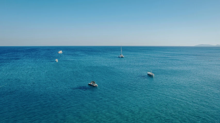 several boats are floating on the blue ocean