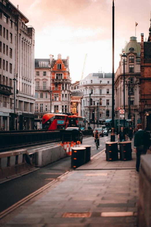 a city street with buildings, people walking and a train on it