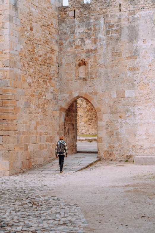 a person walks down an alley way through a stone castle