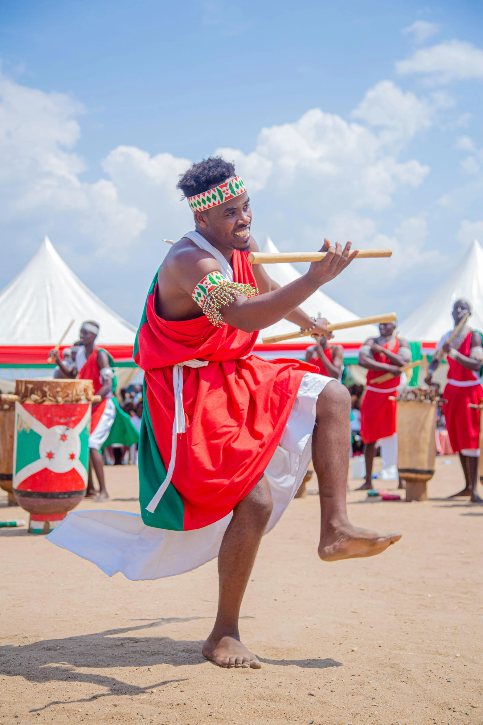 a man in african attire is dancing with a stick