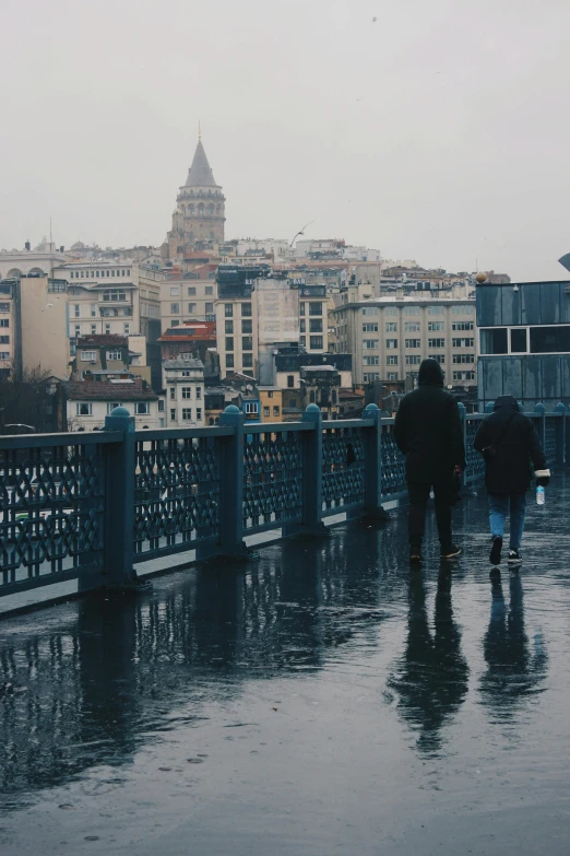 two people walking across a city bridge on a very rainy day