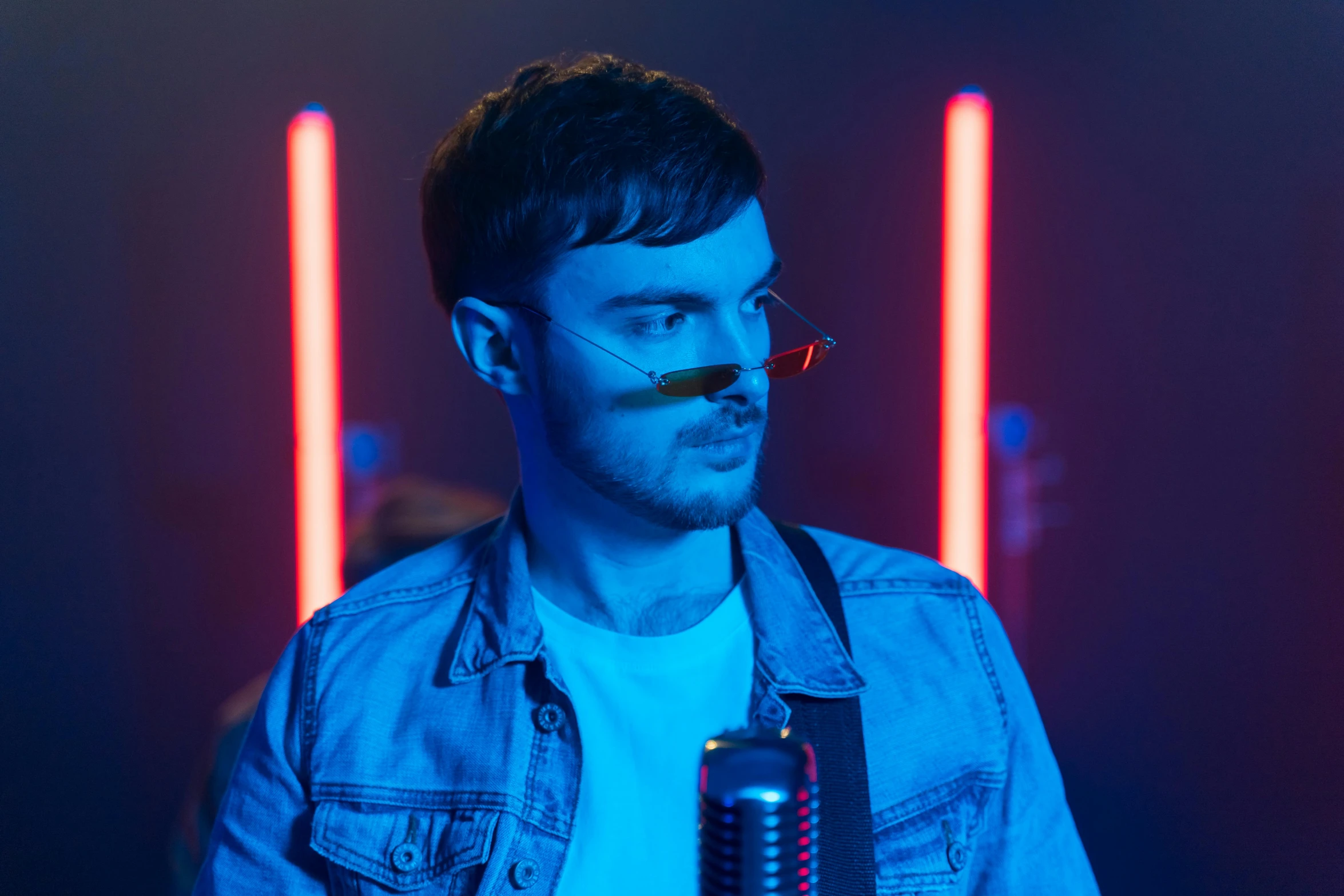 a man wearing glasses in the dark, looks down with glowing glasses