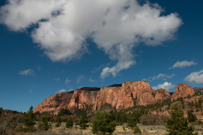 trees and clouds are around a mountain range