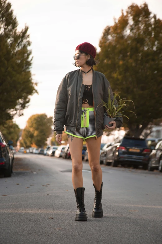 woman wearing shorts and black jacket walks on the street