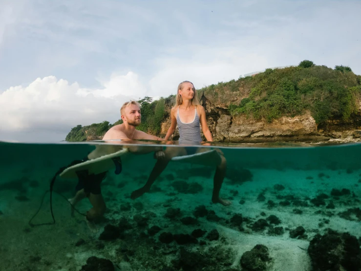 there is a woman and a man in the water looking at an animal