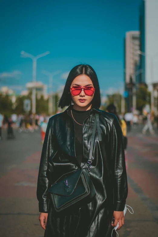 a young woman in black clothing carrying a bag on the street