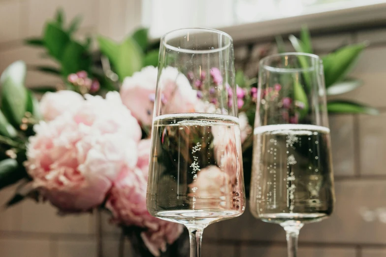 two glasses of champagne with pink flowers in the background