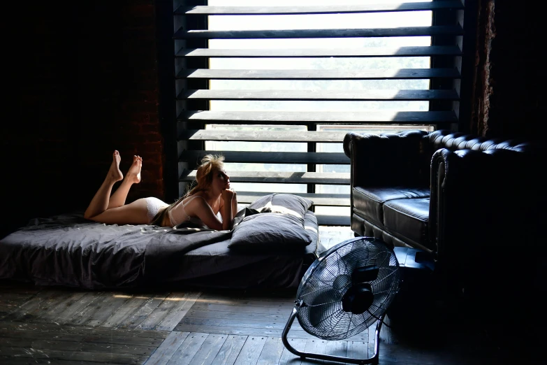 a girl laying on her bed next to the window