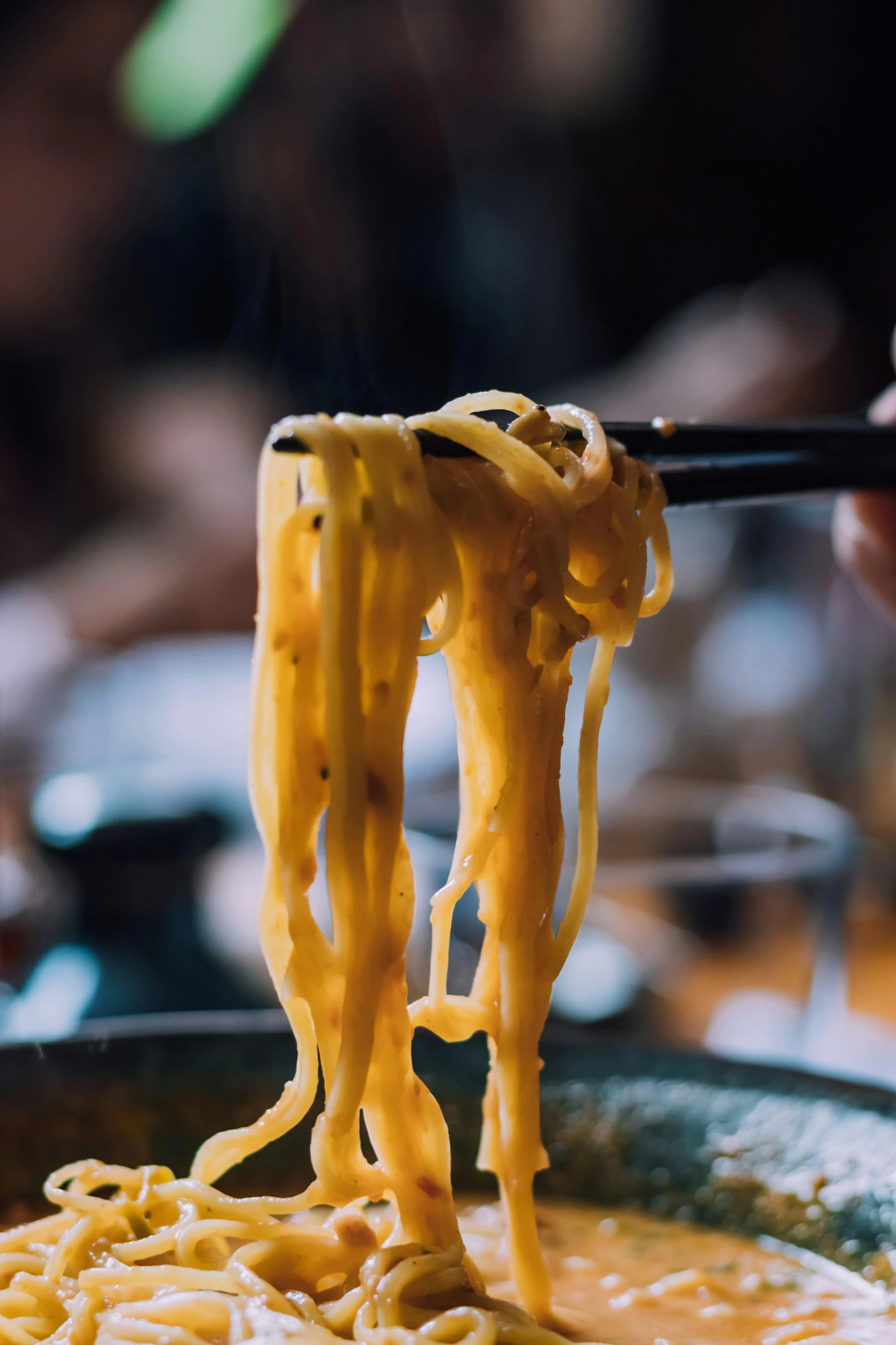 noodles being lifted from a pot with chopsticks