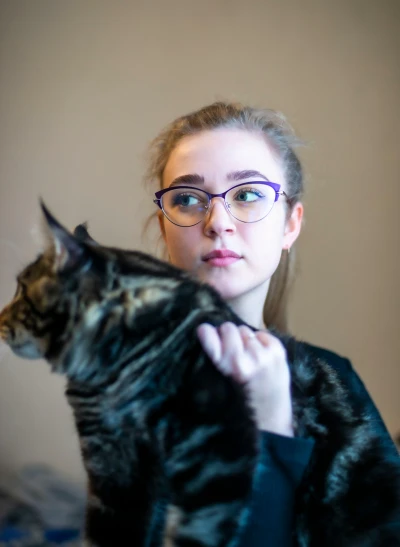 a woman is holding onto a cat wearing glasses