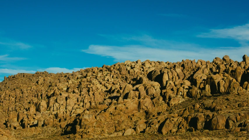 a rocky mountain with grass and blue sky