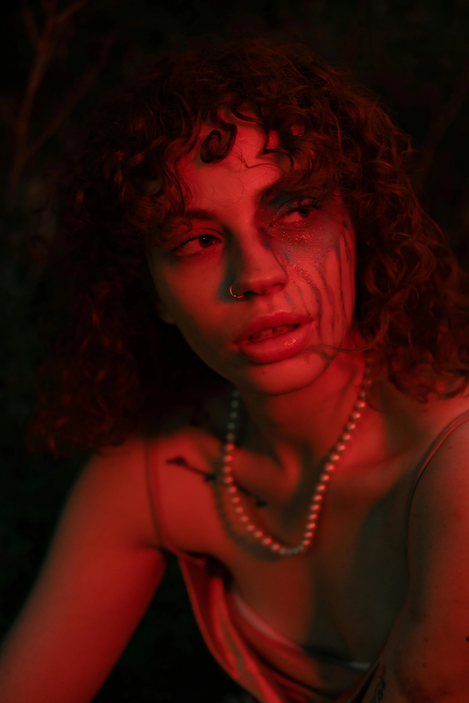 a woman in a tank top poses with red light coming through her hair