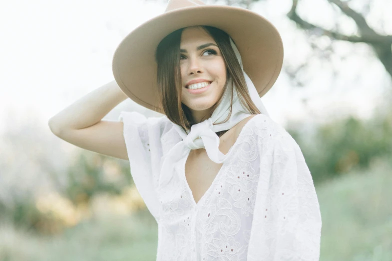 a woman wearing a hat posing in the grass