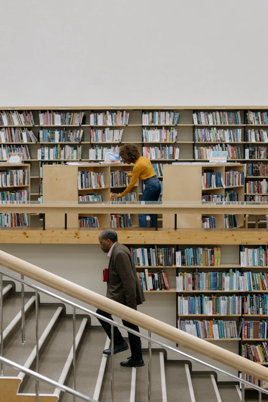 a person standing at the top of a stair case with lots of books