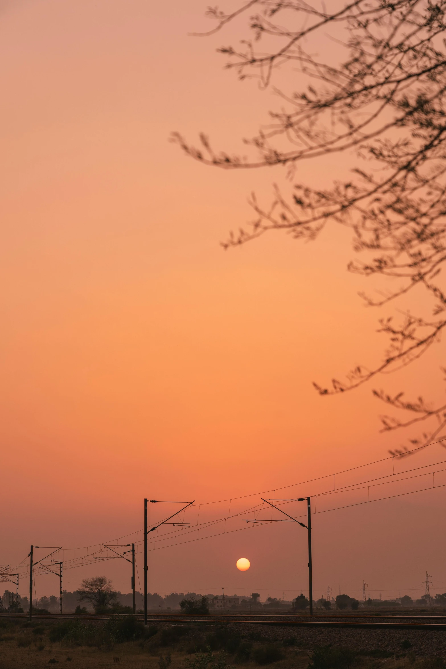 the setting sun seen through a telephone line fence