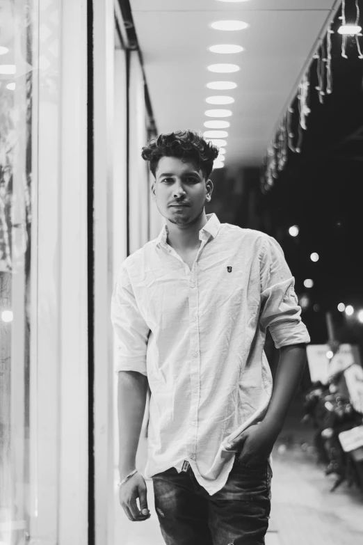 black and white pograph of a man leaning against the glass door of a store