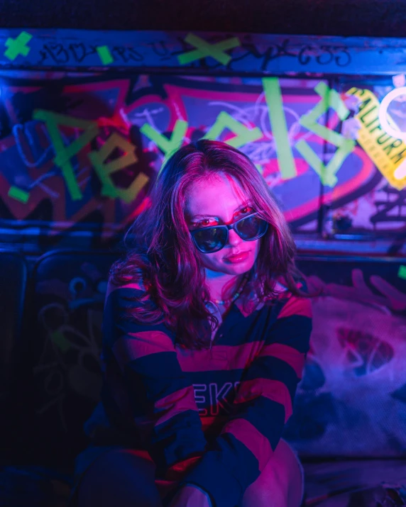 a woman sitting in front of a colorful wall