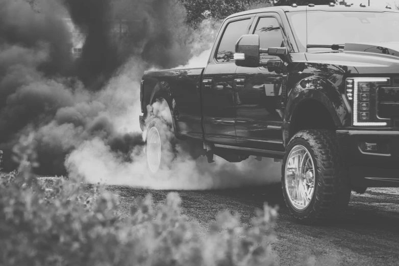 an black and white po of the front end of a truck smoking out its tires