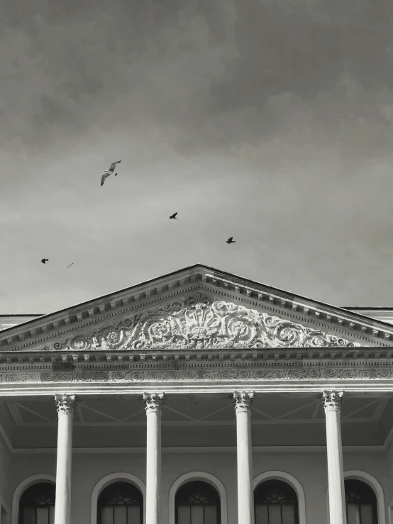 a white building has pillars and pillars and a cloudy sky