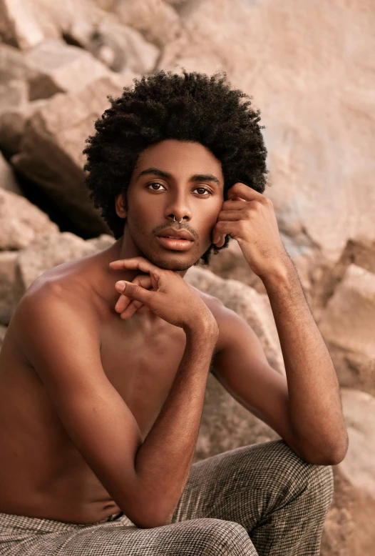 a man poses for a pograph while sitting on rocks