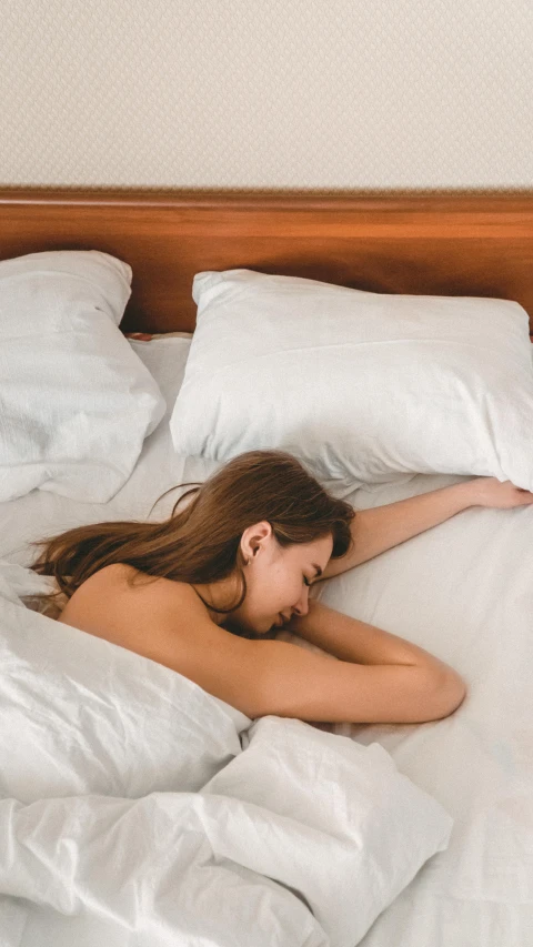 a young woman lies  on a white bed