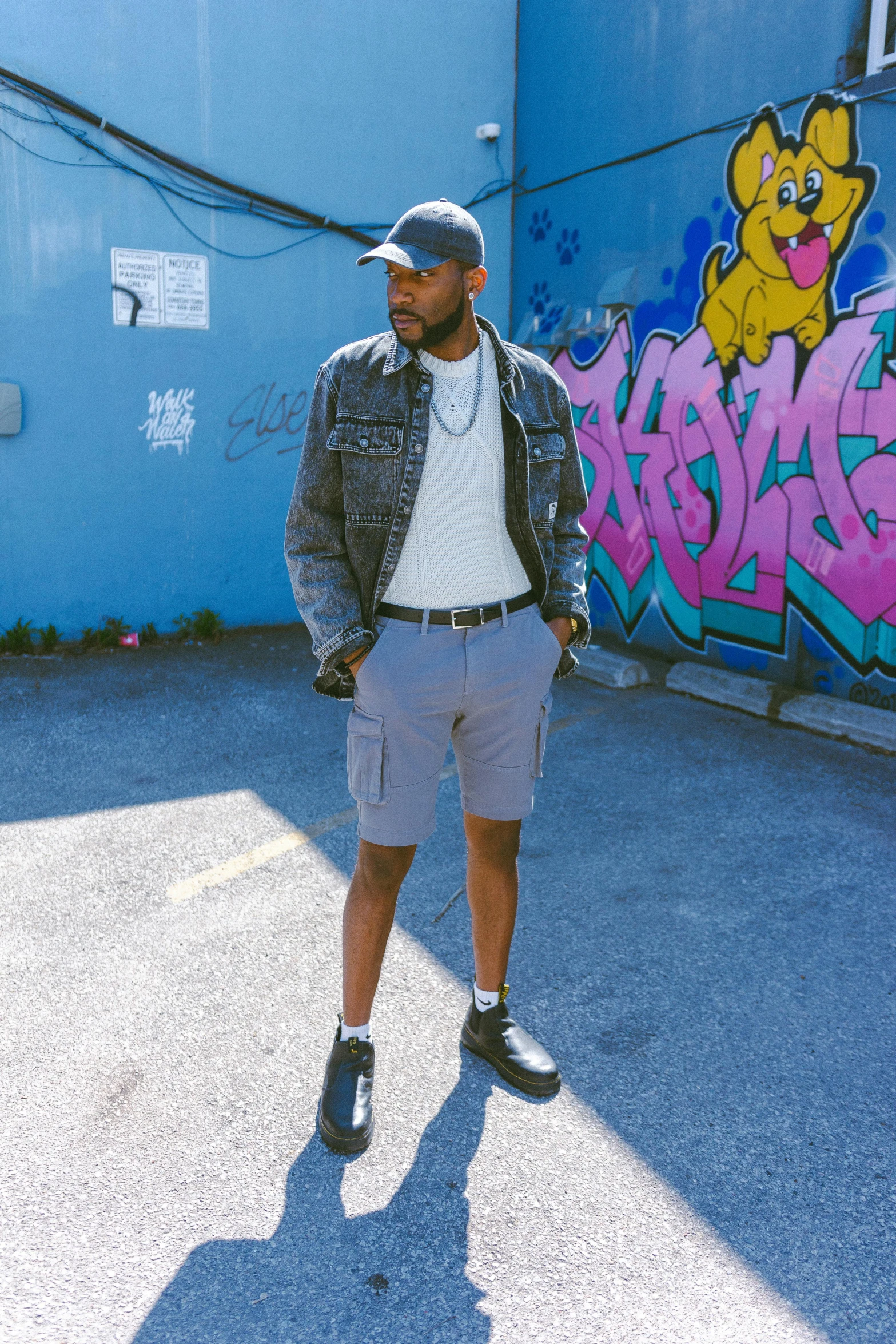 man standing in front of blue wall with graffiti