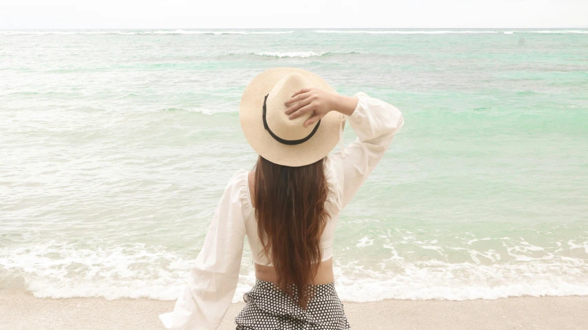 a woman with a hat standing in front of a body of water