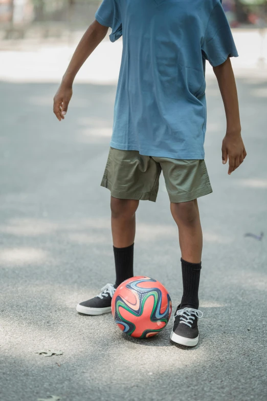 a young man standing next to a red ball on the street