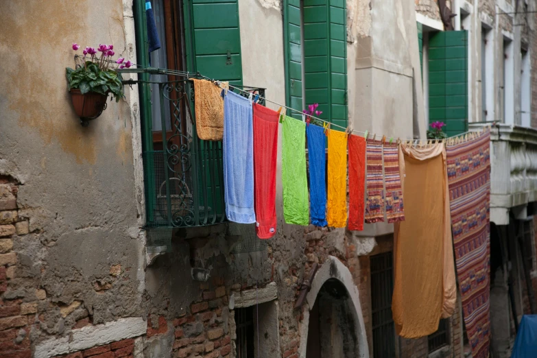 multicolored towels hang on the balcony of a house